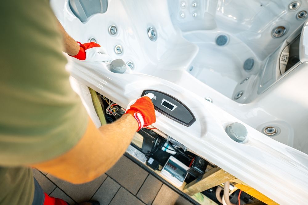Person in red gloves repairing a white hot tub control panel indoors