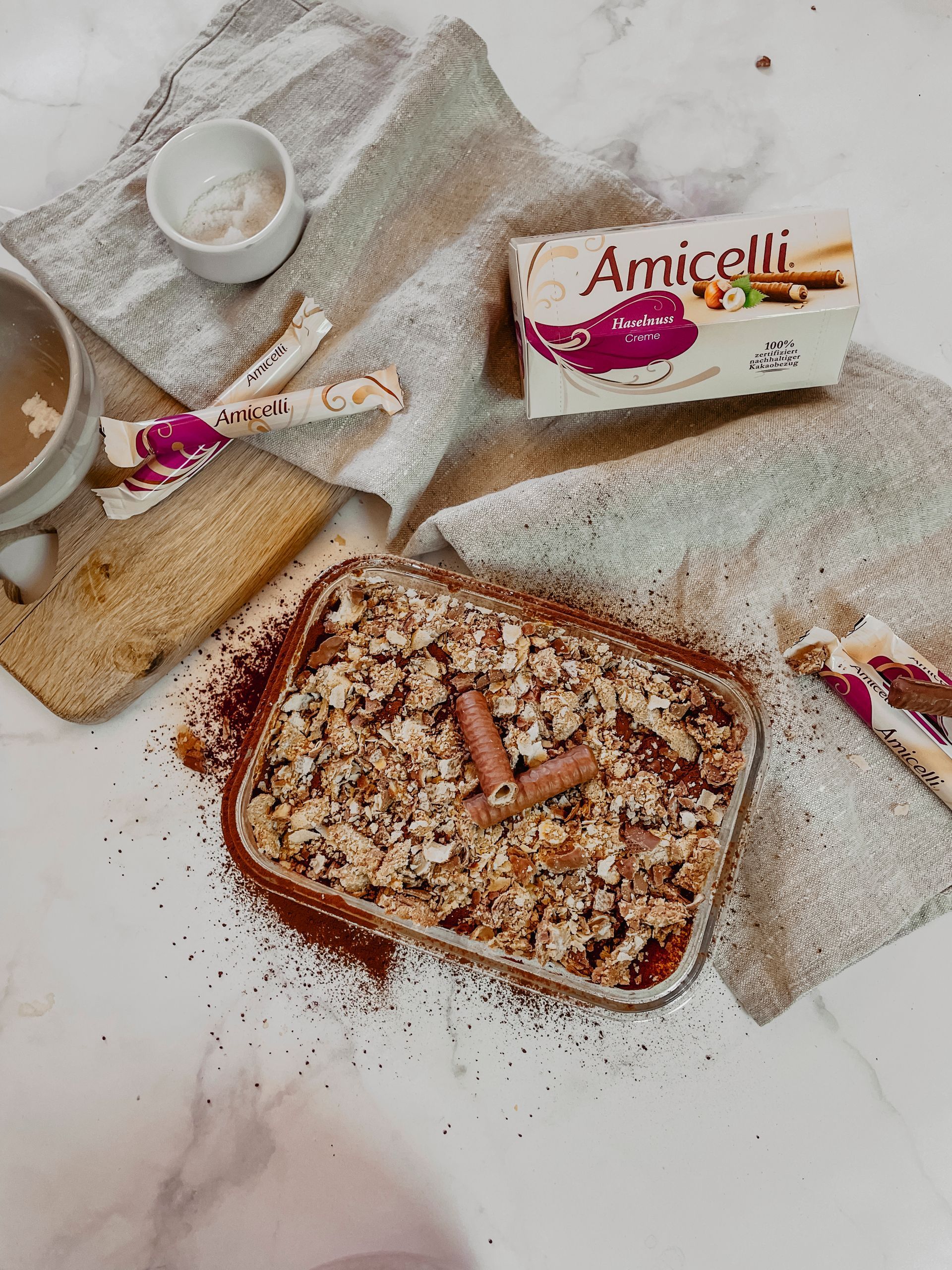 A casserole dish filled with food is sitting on a table next to a box of amicielli.