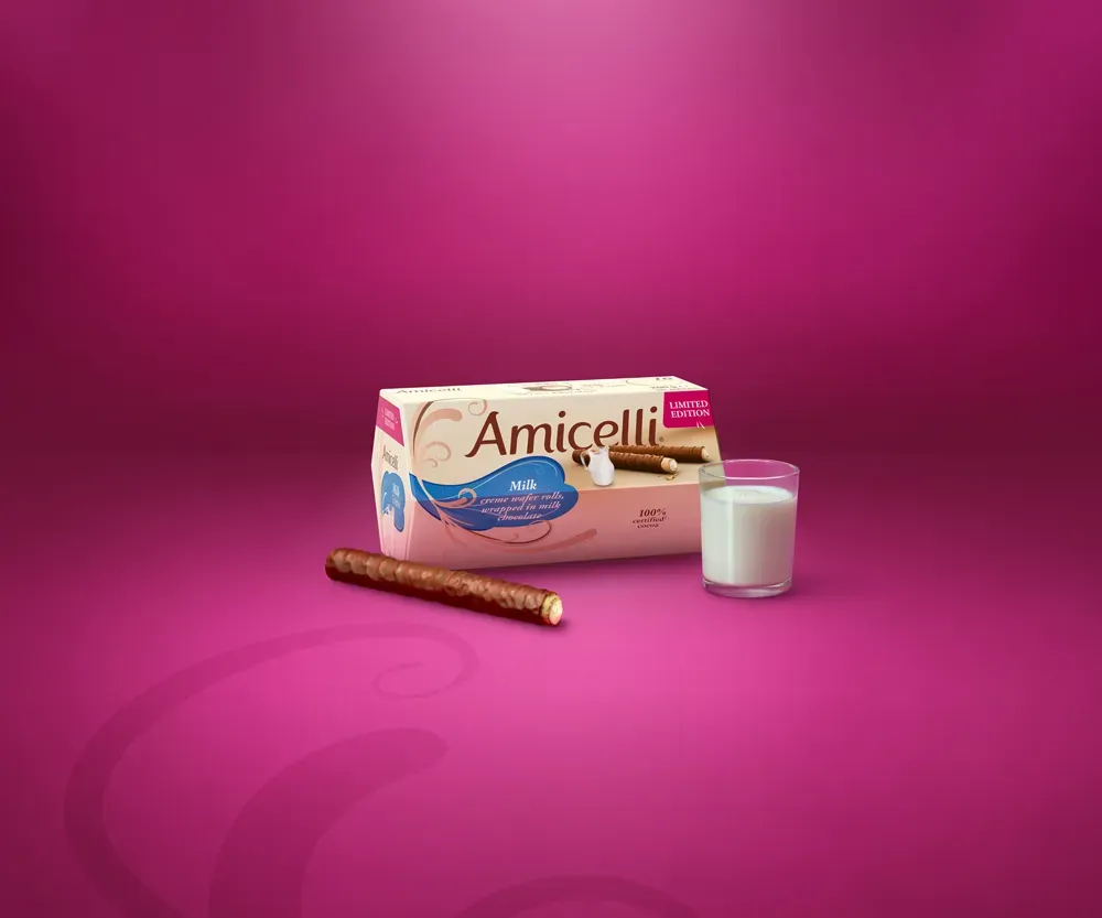Amicelli box with chocolate wafers and a glass of milk on a pink background