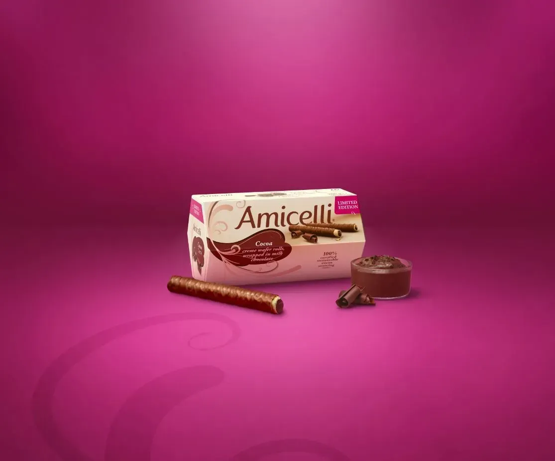 A box of amicielli chocolate wafer sticks on a pink background.