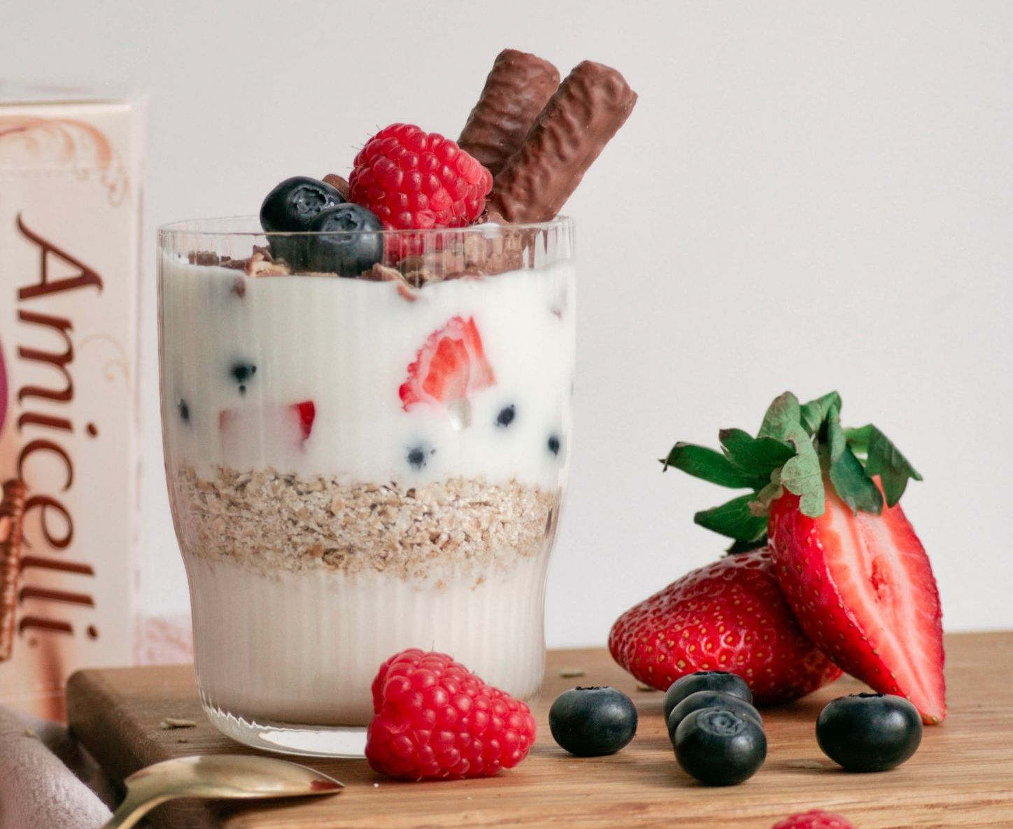 A glass of yogurt with raspberries and blueberries on top