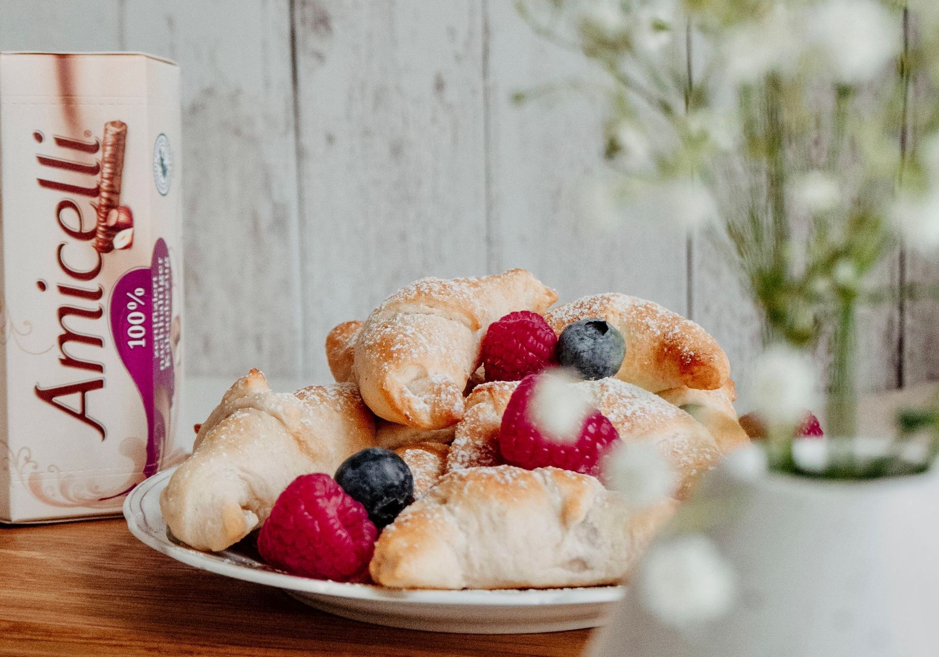 A plate of croissants with raspberries and blueberries on a table