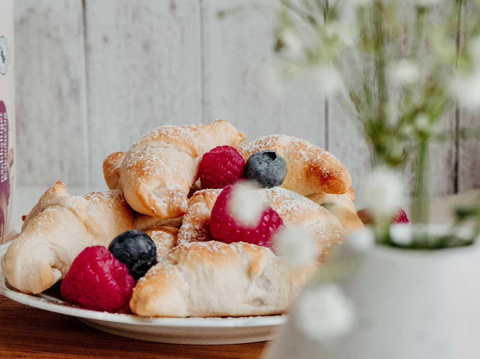A plate of croissants with raspberries and blueberries on a table
