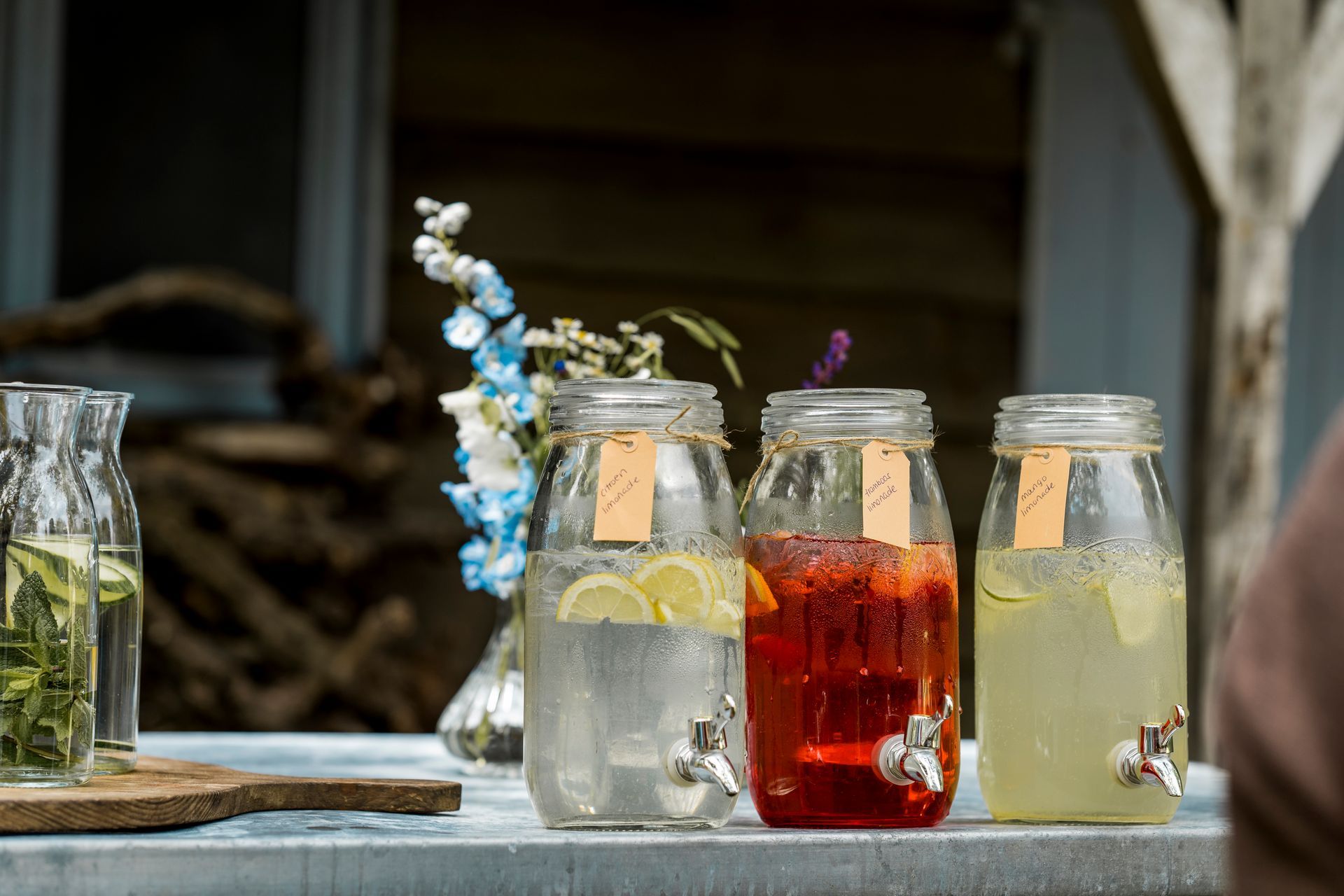 Drie glazen drankdispensers met etiketten, gevuld met kleurrijke drankjes.