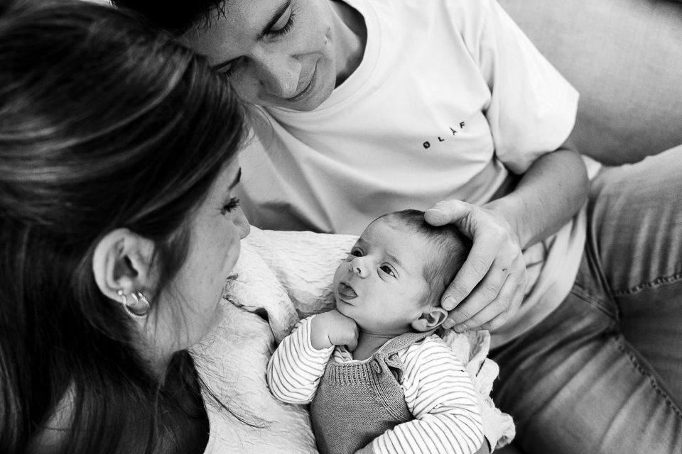 Ouders kijken vol liefde naar hun pasgeboren baby in hun armen. Zwart-witfoto.