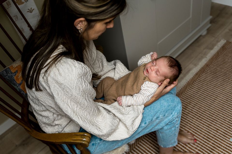 Vrouw met een slapende baby op schoot, binnen.