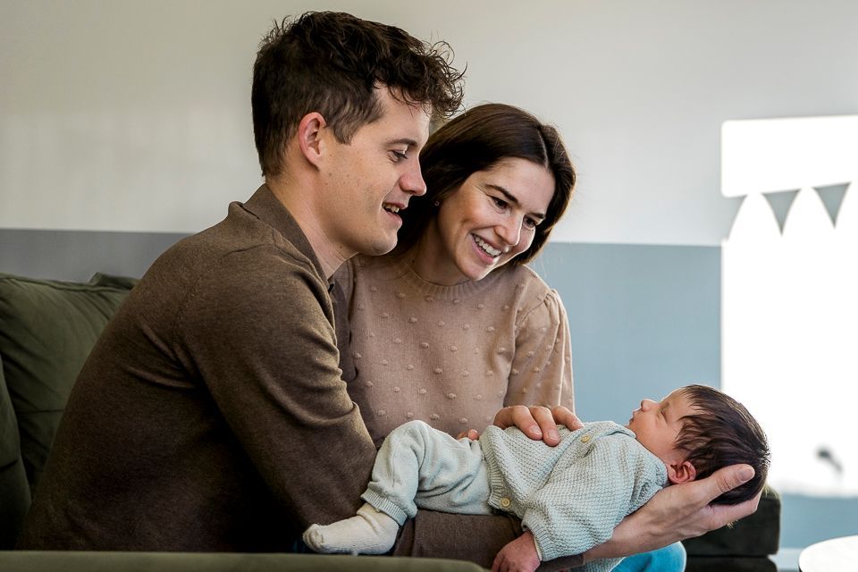 Ouders glimlachen naar hun pasgeboren baby in huis.