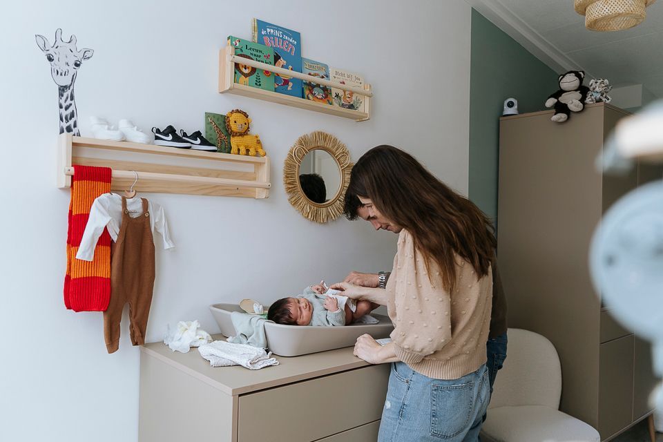 Ouders die een baby luier verschonen op een commode in een babykamer.