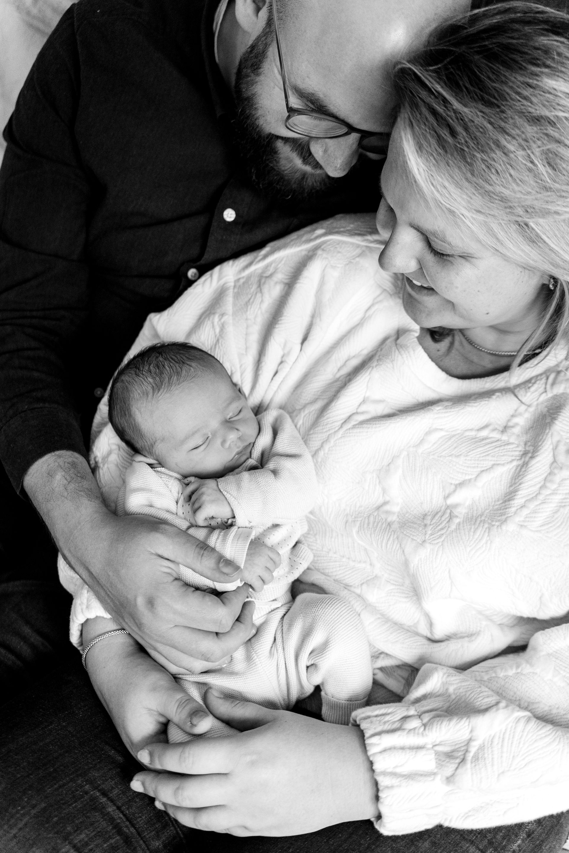 Ouders die een pasgeboren baby knuffelen. Zwart-witfoto.