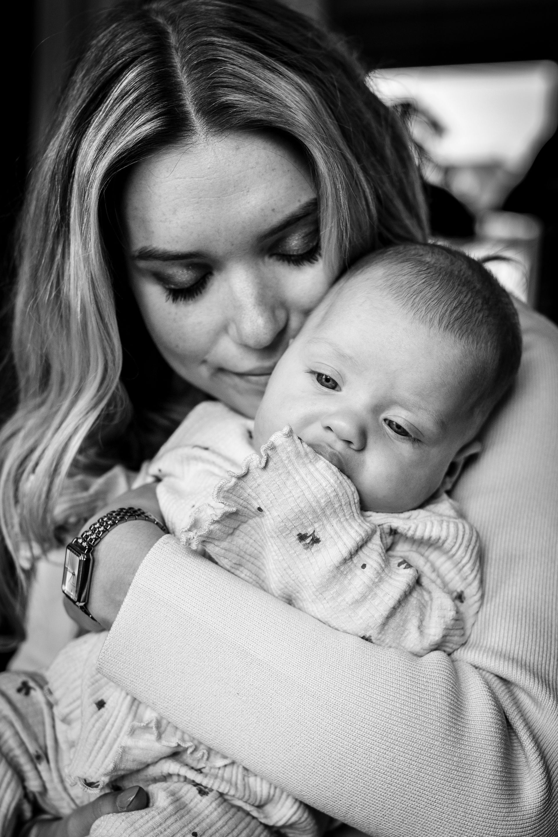 Vrouw houdt een baby teder vast, beiden kijken naar beneden. Zwart-witfoto.
