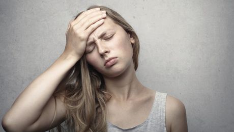 A woman holding her head because of Vertigo