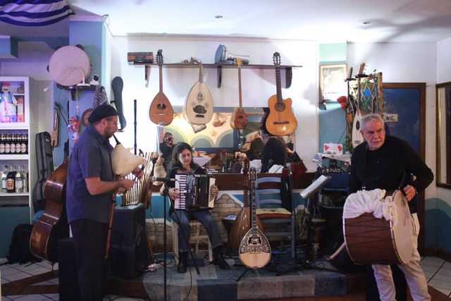Musicisti che si esibiscono al chiuso con chitarre e batteria in una stanza accogliente e piena di strumenti.