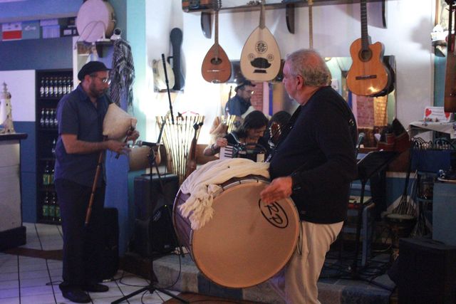 Tre musicisti che suonano in un negozio di musica con le chitarre appese al muro.
