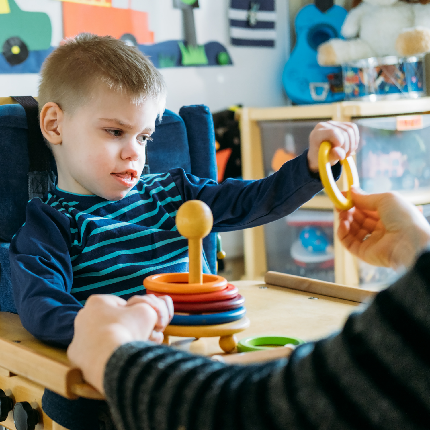 A child in a wheelchair is playing with a stacking toy
