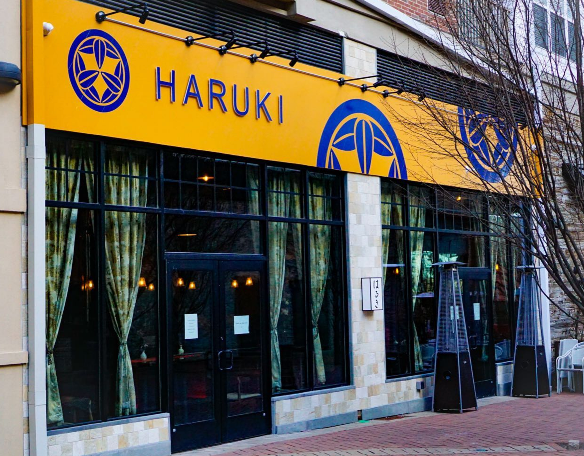Haruki restaurant exterior with yellow and blue signage, glass windows, and outdoor heaters.