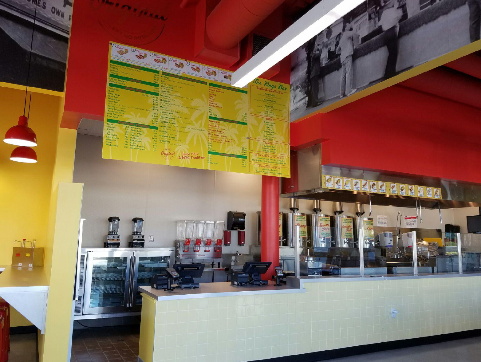 Interior view of a restaurant with a menu, food prep area, and red and yellow decor.