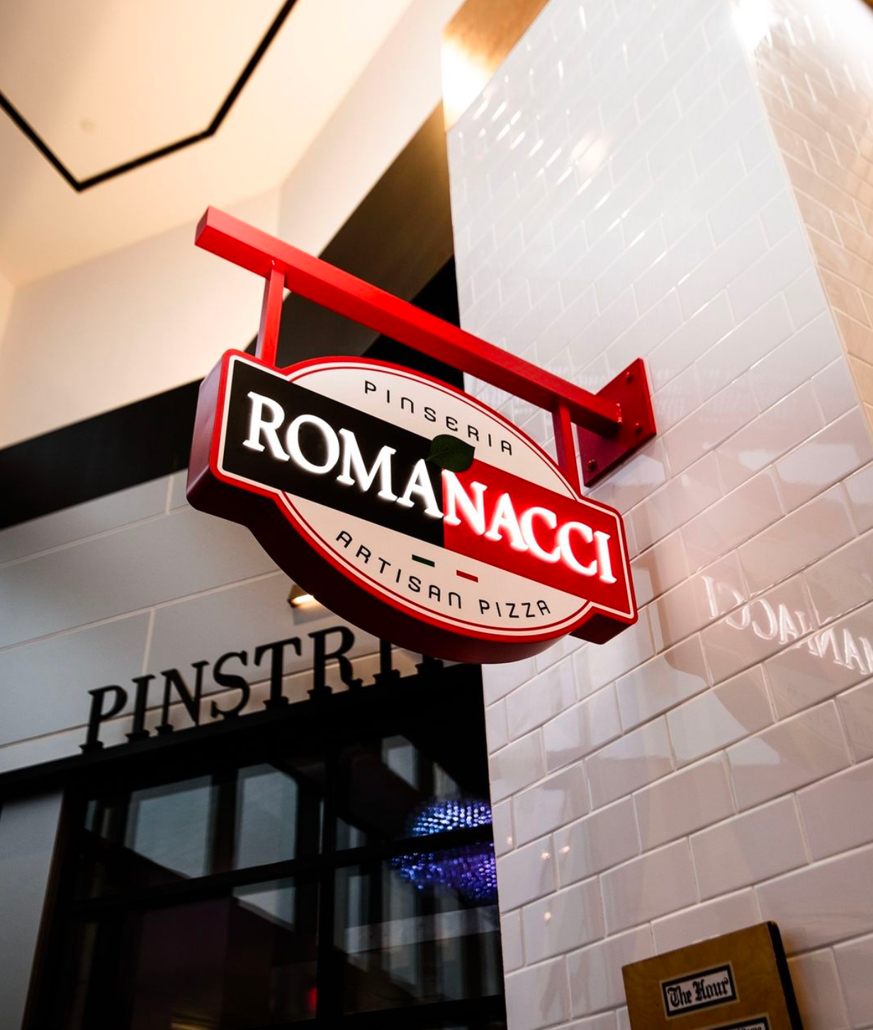 Sign for Romanacci Pizzeria with a red and black design.