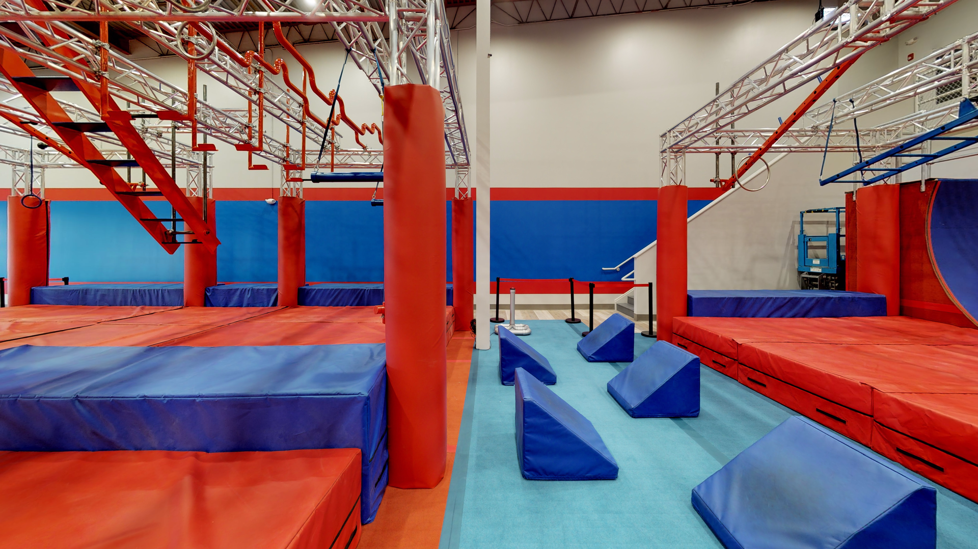 Indoor ninja warrior gym with red and blue obstacles.