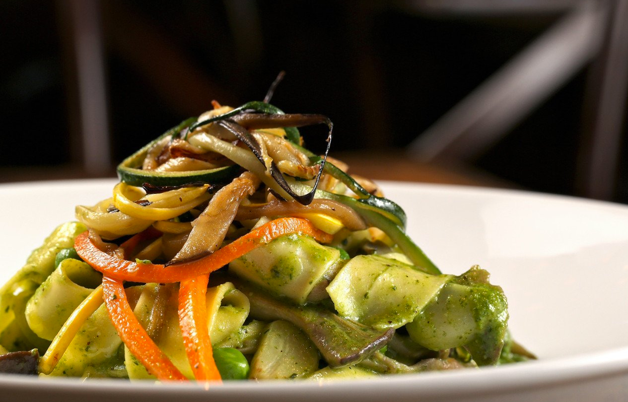 Pasta dish with zucchini ribbons, carrots, and green sauce.