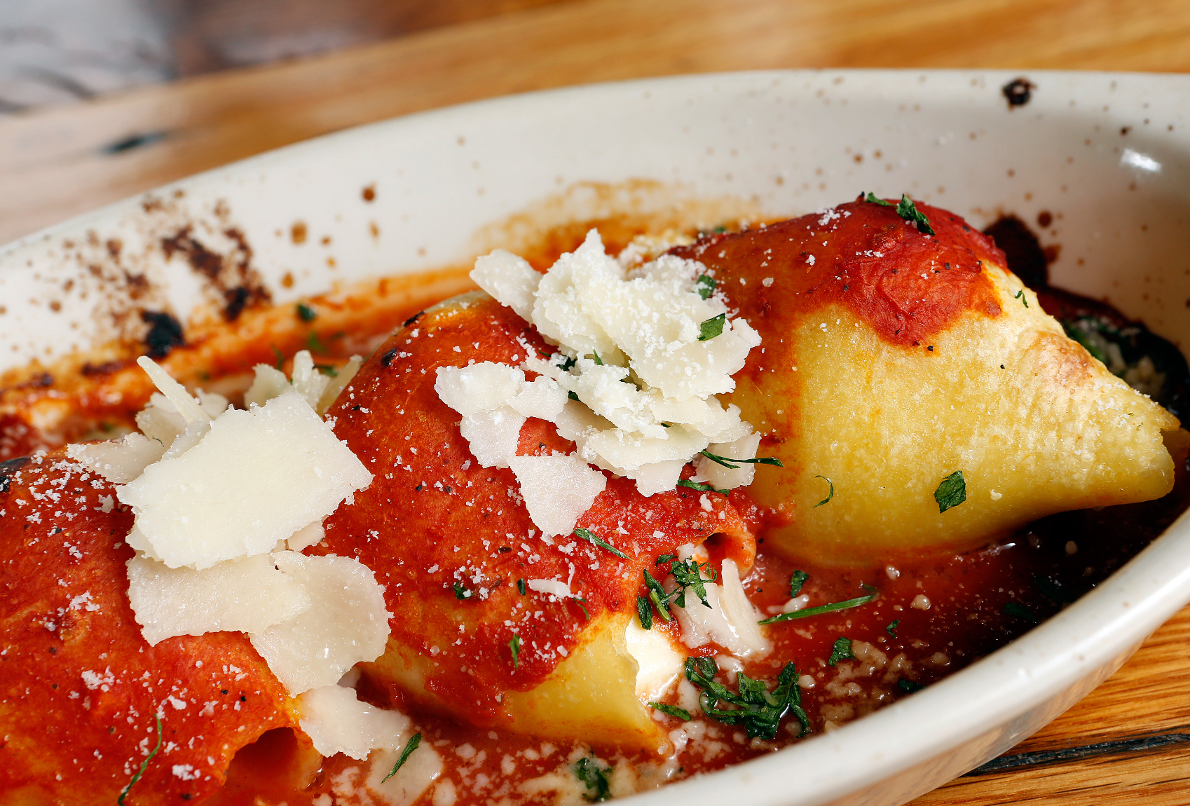Baked pasta rolls with tomato sauce and shaved parmesan cheese.