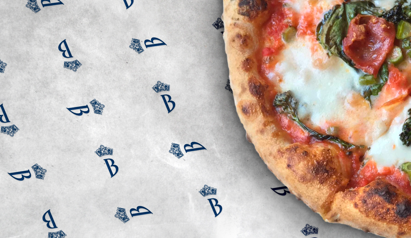 Pizza on patterned paper. Crust is golden brown. Toppings include white cheese, red sauce, and green peppers.