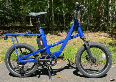 Blue electric bike parked on a paved path in a park.
