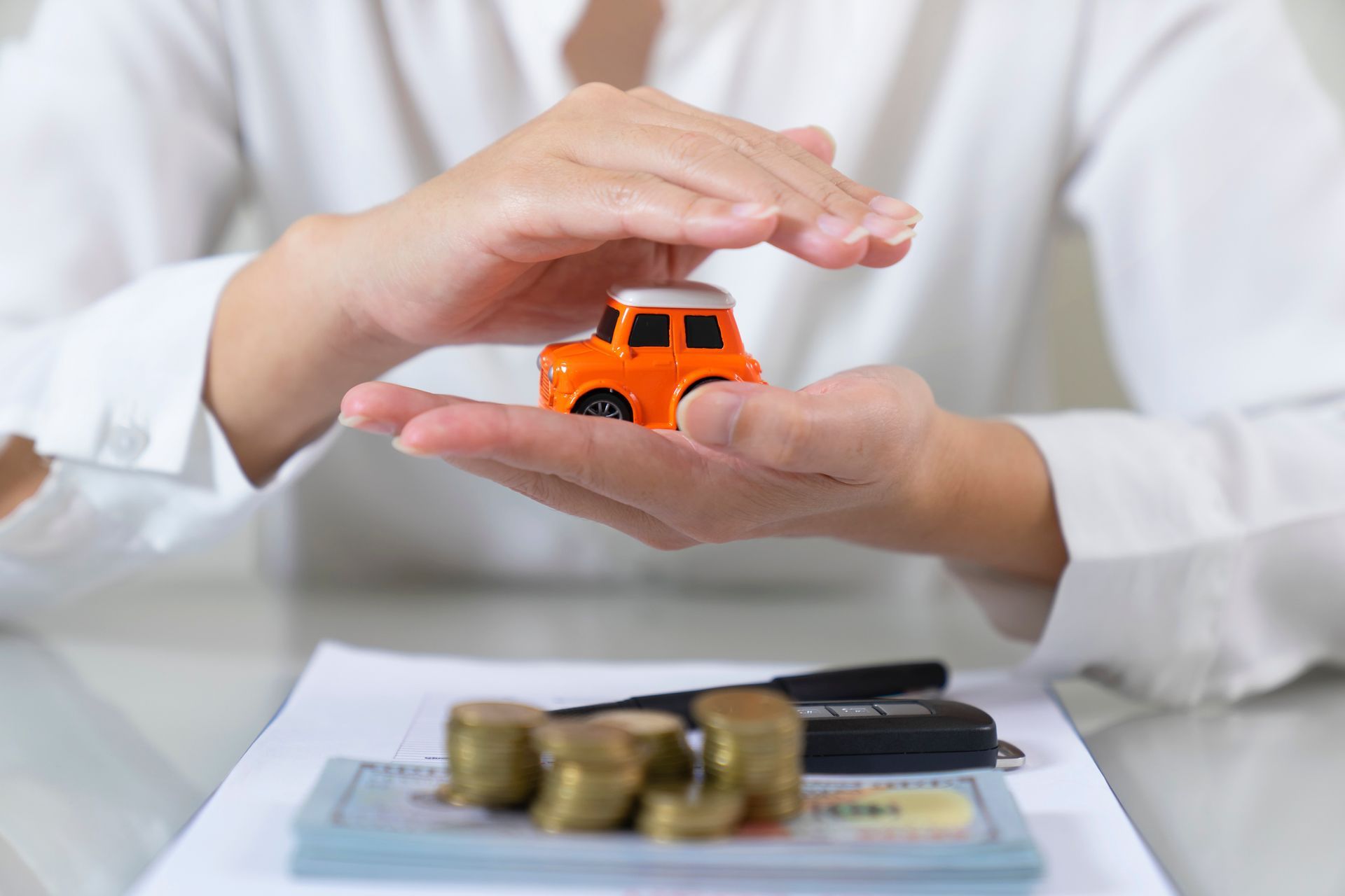 A close-up of a man holding an orange toy car, symbolizing an auto insurance agent. A close-up of a man holding an orange toy car, symbolizing an auto insurance agent.