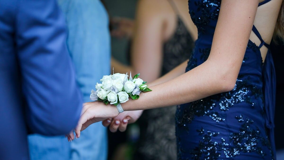 Woman in a navy blue sequined dress with a corsage on her wrist, at a formal event.