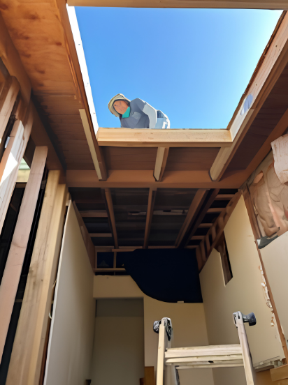 Person working on a ceiling opening inside a construction site with exposed wooden beams and blue sky above