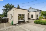Single-story cream house with large windows and a driveway in front