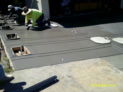 Worker installing gray flooring panels on a rooftop under construction