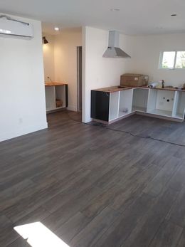 Empty modern kitchen and living area with gray floors and white walls, under construction or unfurnished.