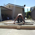 Worker aligning wooden boards on a driveway in front of a house