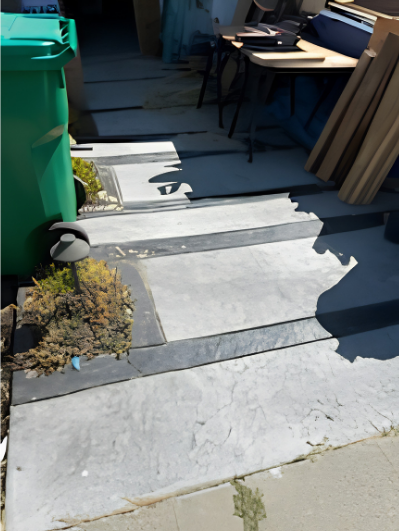 Outdoor concrete steps beside a green bin and table in sunlight, leading to a shaded patio area