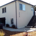 Two-story beige house with exterior staircase, windows, and the number 3078 on the wall