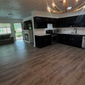 Open-plan kitchen and living room with dark cabinets, wood floors, and sliding glass doors.