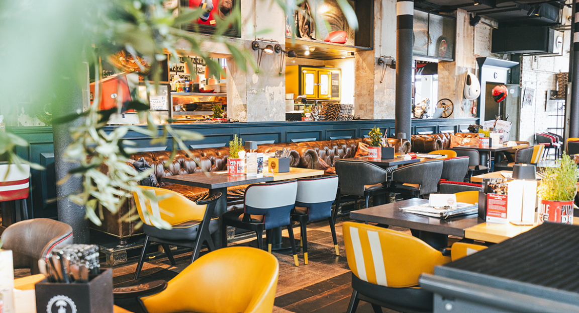 Stilvolles Restaurantinterieur mit gelben Stühlen, Tischen, Regalen und warmer Ambientebeleuchtung