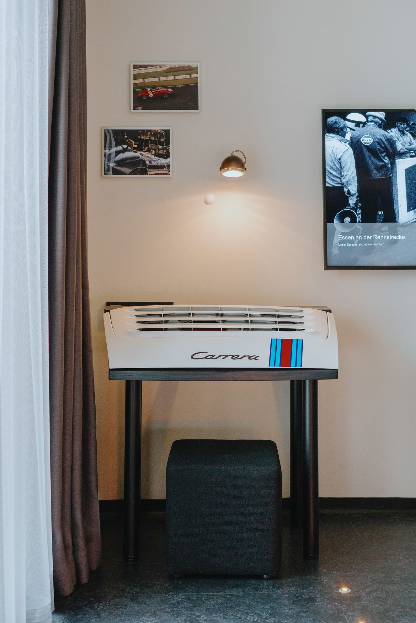 Gerahmte Fotos, eine Wandleuchte und ein kleiner Tisch mit einem Canon-Drucker in einem minimalistischen Raum