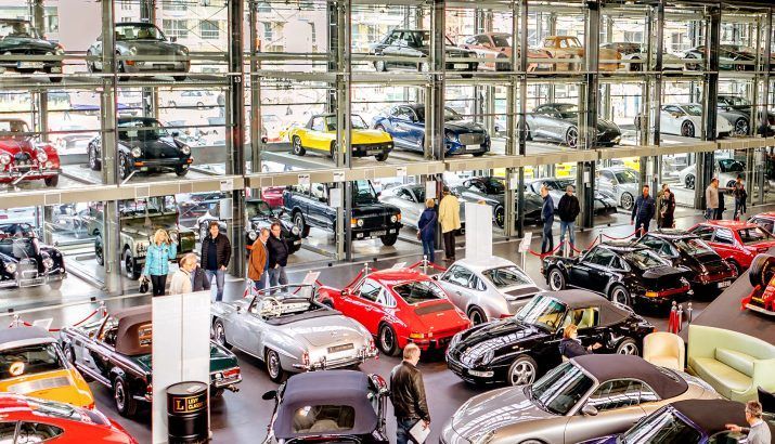 Klassische Indoor-Autoausstellung mit Reihen farbenfroher Oldtimer und Besuchern auf mehreren Ebenen