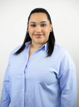 A woman in a blue shirt is smiling for the camera.