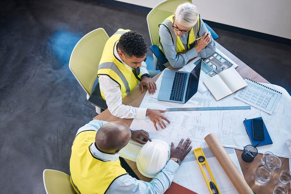 A group of construction workers are sitting around a table looking at a blueprint.
