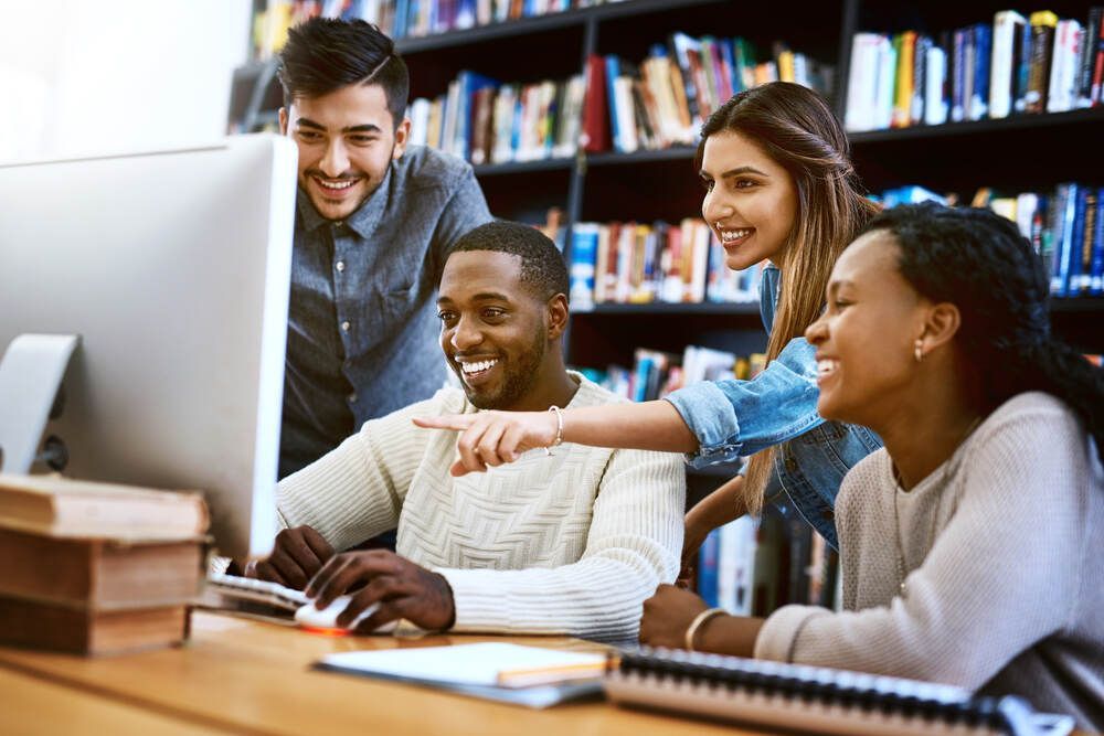 A group of people are looking at a computer screen in a library.