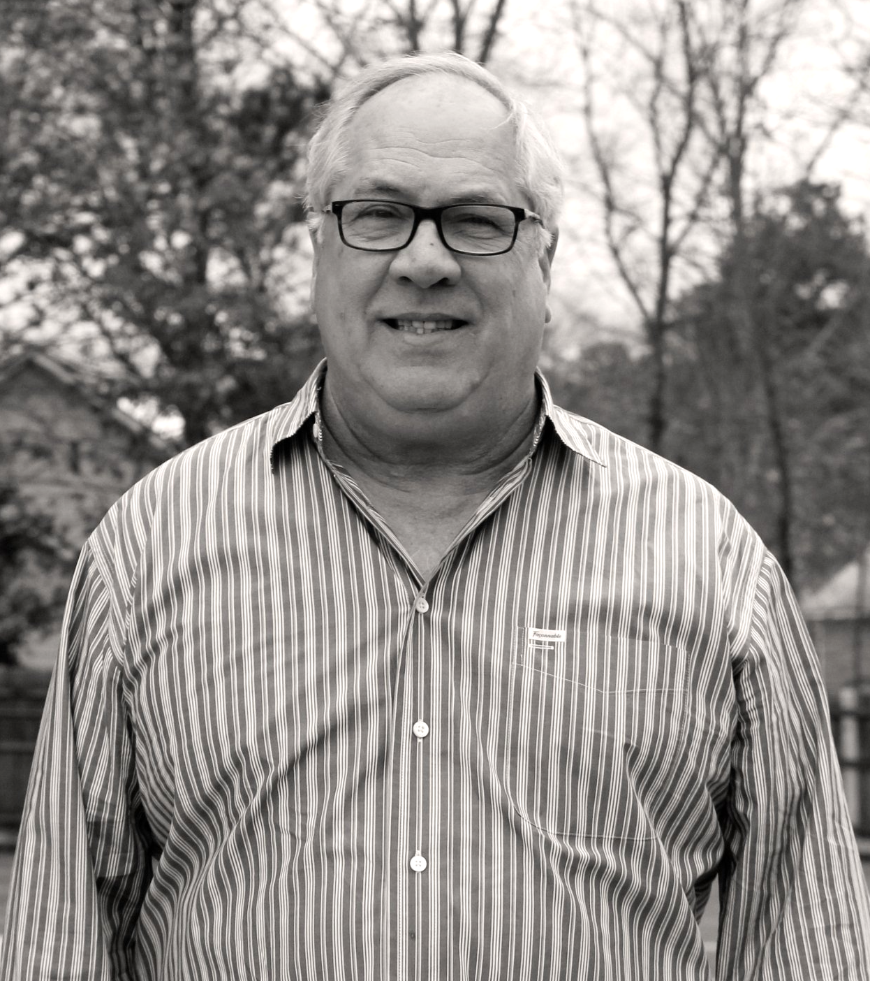 Man wearing glasses and a striped shirt smiles outdoors. Mike Wayman