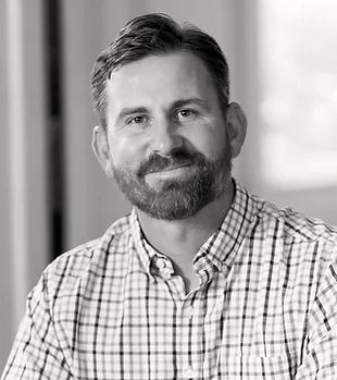 Man with short hair and beard wearing a plaid shirt, smiling at the camera. Josh Yates