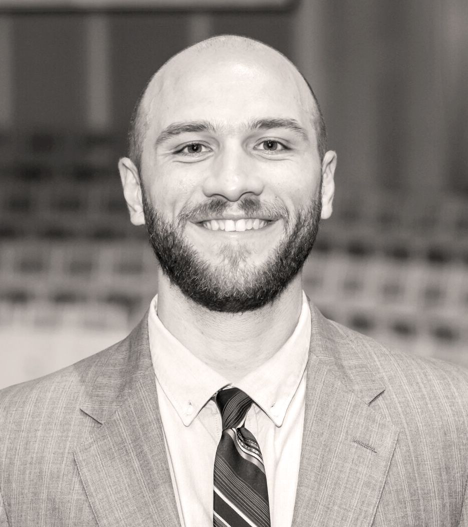 Man wearing a suit smiles at the camera. Arron Wine