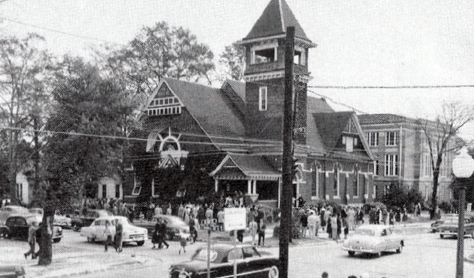 Vintage photograph of Auburn University Chapel, building with a tower, people gathered outside, cars parked nearby.