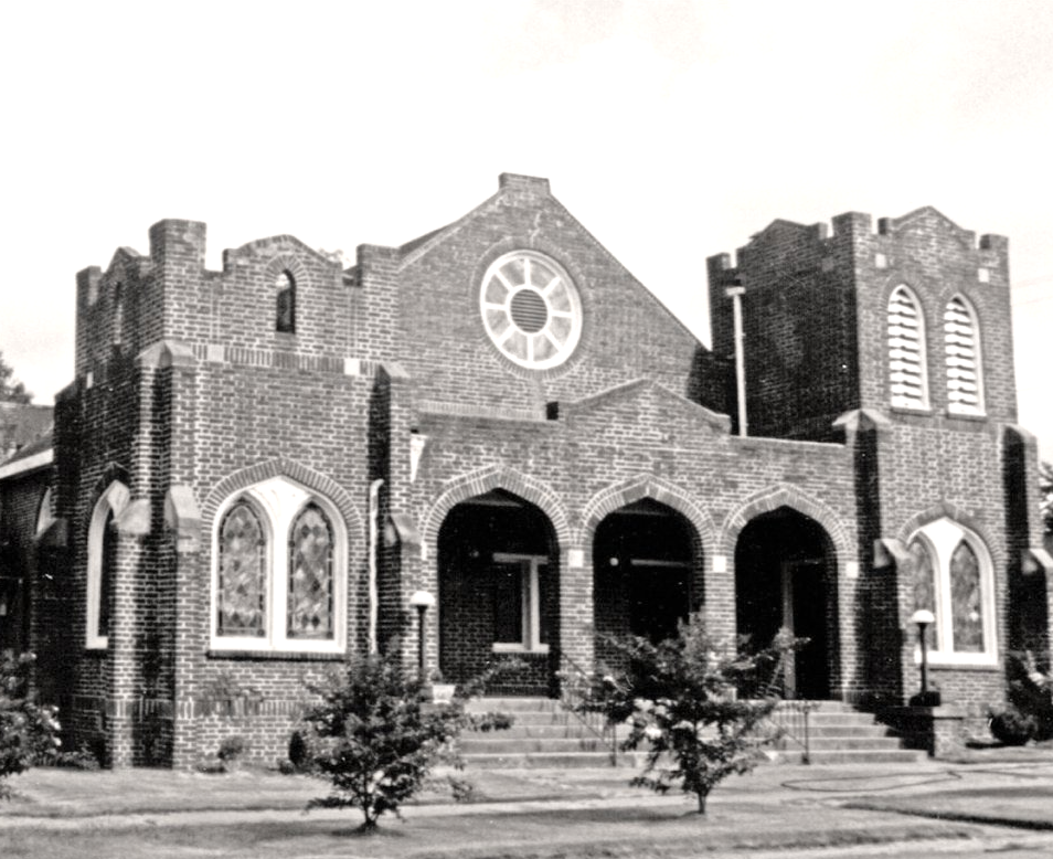 Brick church building with arched entrance and two side towers, stained glass windows. First Presbyterian Church Opelika