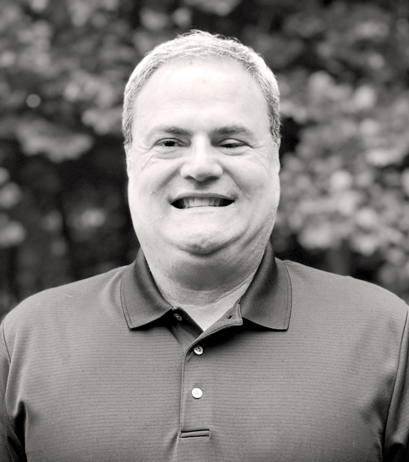Smiling man with short graying hair wearing a dark polo shirt, standing outdoors. Raul Pacheco