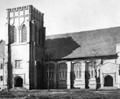 Historic brick church with a tall tower and arched windows under a dark roof. Trinity Church Opelika