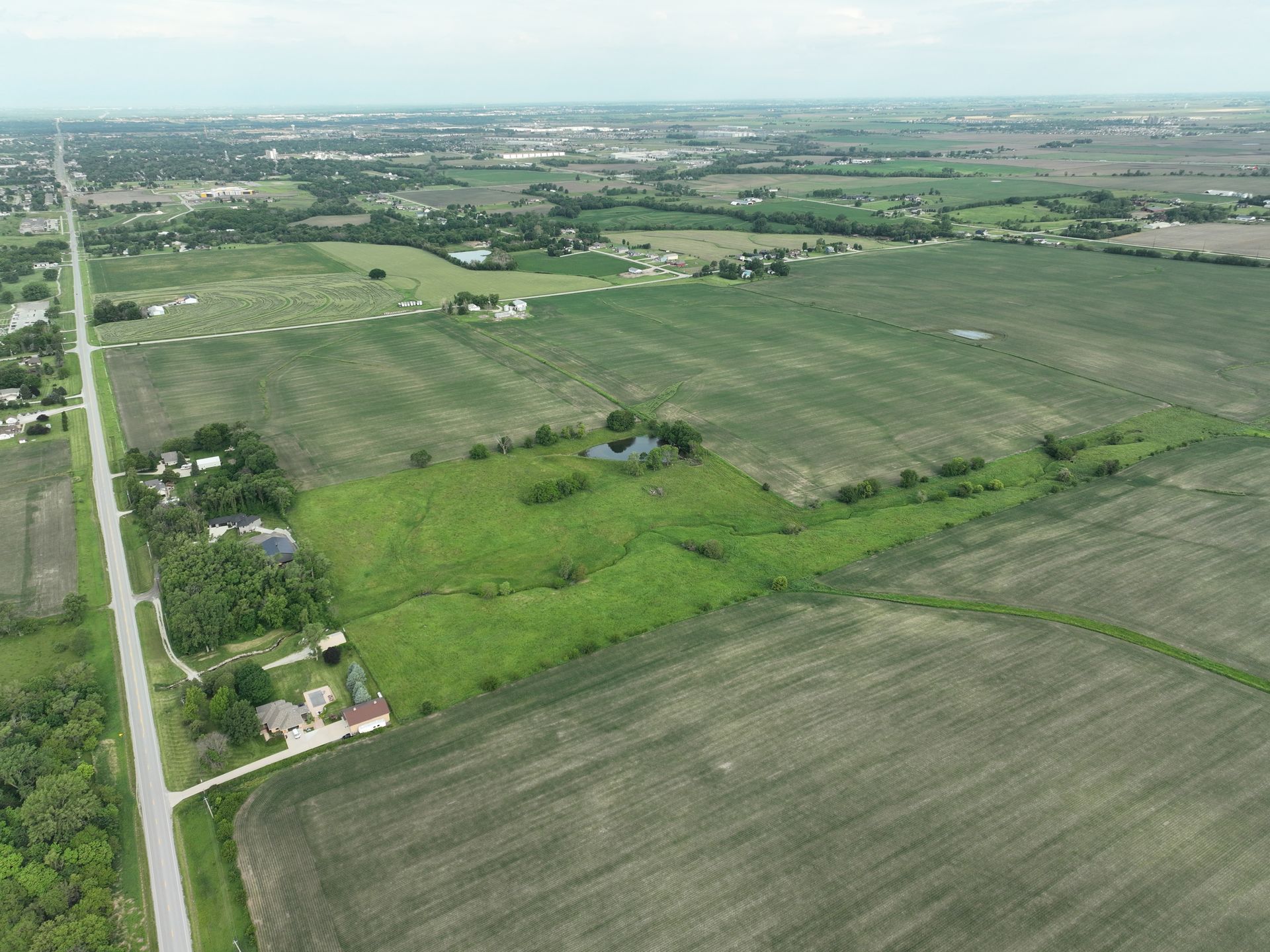 An aerial view of a lush green field with a road going through it